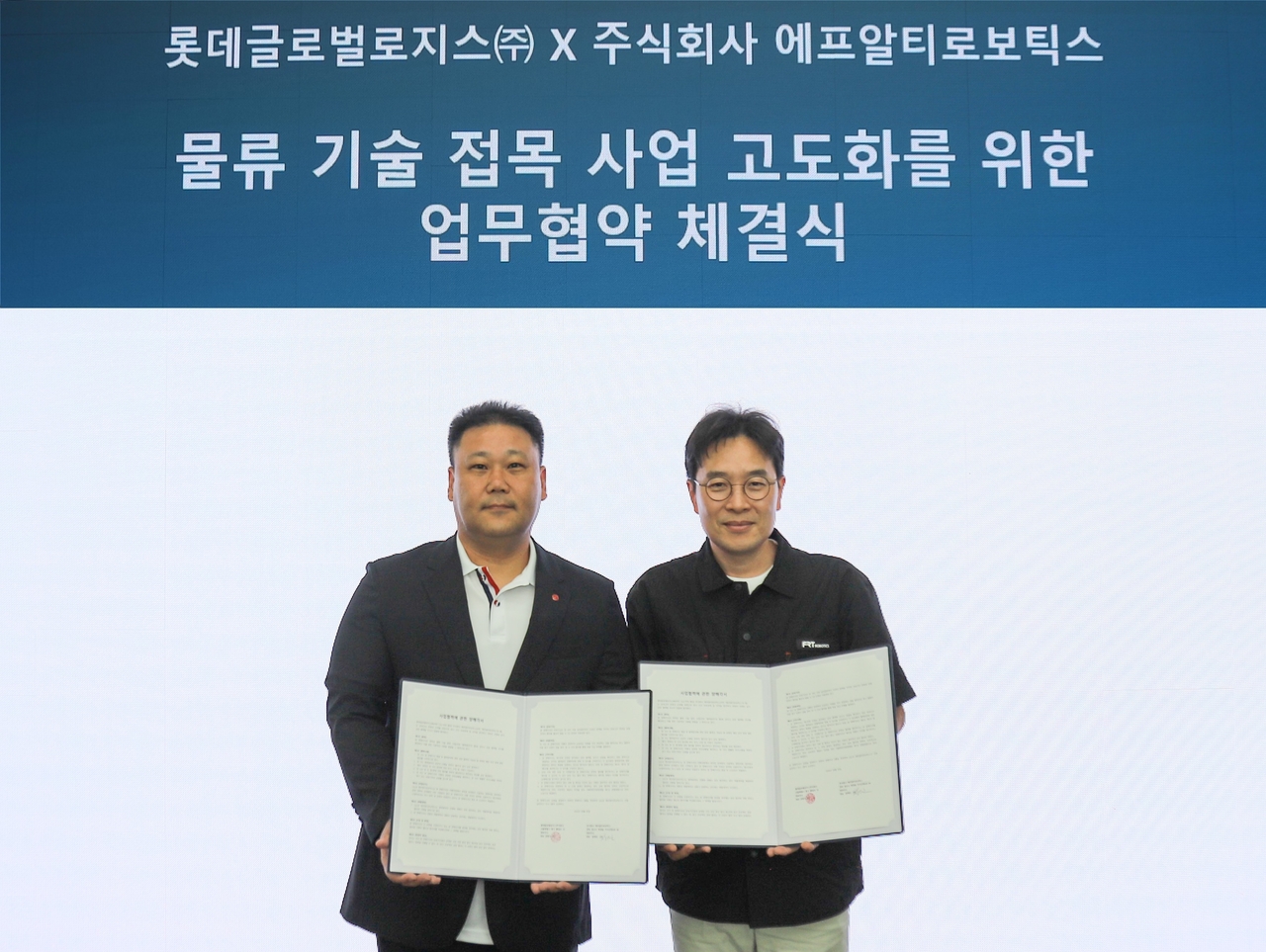 육창용 롯데글로벌로지스 테크놀로지부문장(왼쪽)과 장재호 에프알티로보틱스 대표가 기념 촬영을 하고 있다. [롯데글로벌로지스 제공]