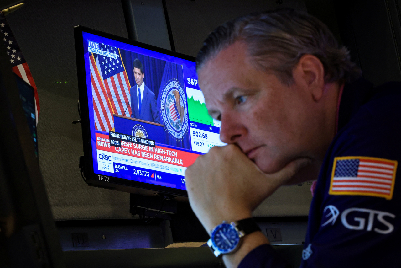 A trader works on the floor of the New York Stock Exchange in New York on Wednesday as a screen shows Federal Reserve Chair Kevin Warsh's news conference following the Fed's interest rate announcement. [Reuters]