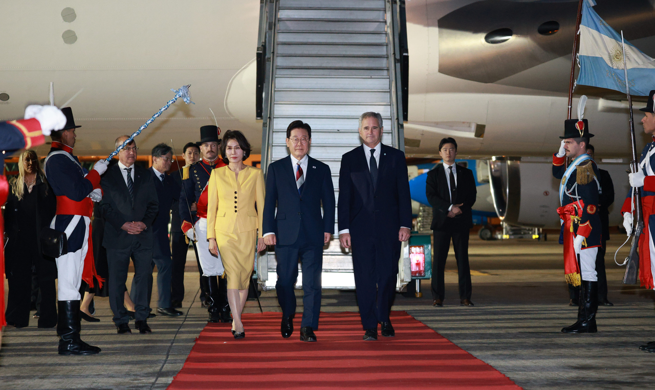 President Lee Jae Myung and first lady Kim Hea Kyung walk with Argentine Foreign Minister Pablo Quirno upon their arrival at Ezeiza International Airport in Buenos Aires, Argentina, Thursday. (Yonhap)