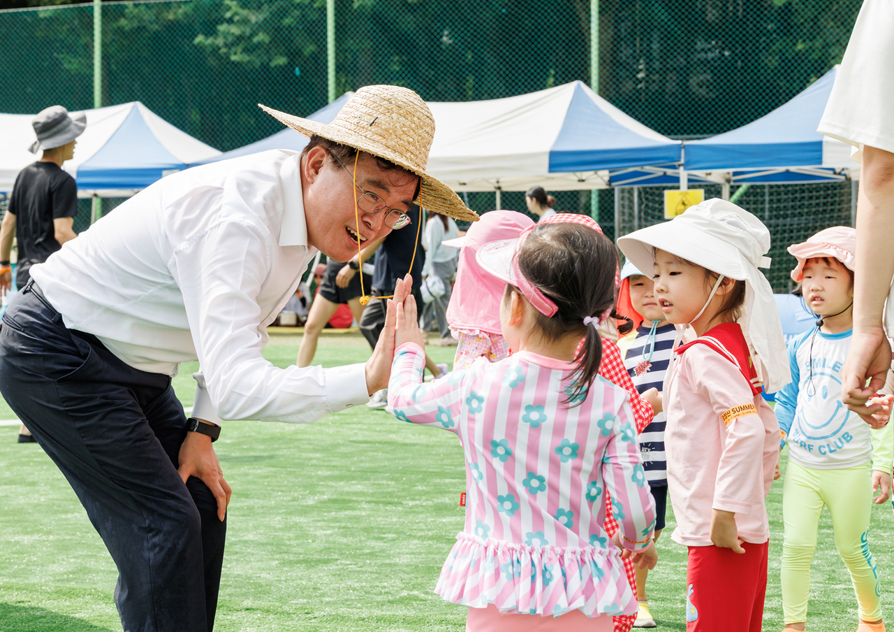 진교훈 강서구청장이 우장산 워터파크에서 어린이와 하이파이브를 하고 있다.