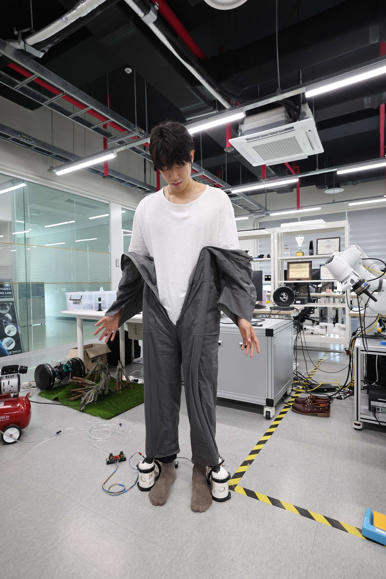 Hwang Jae-yun, a graduate student in the Department of Civil and Environmental Engineering at the Korea Advanced Institute of Science and Technology, demonstrates a self-dressing robot at KAIST in Daejeon on Monday. (KAIST)