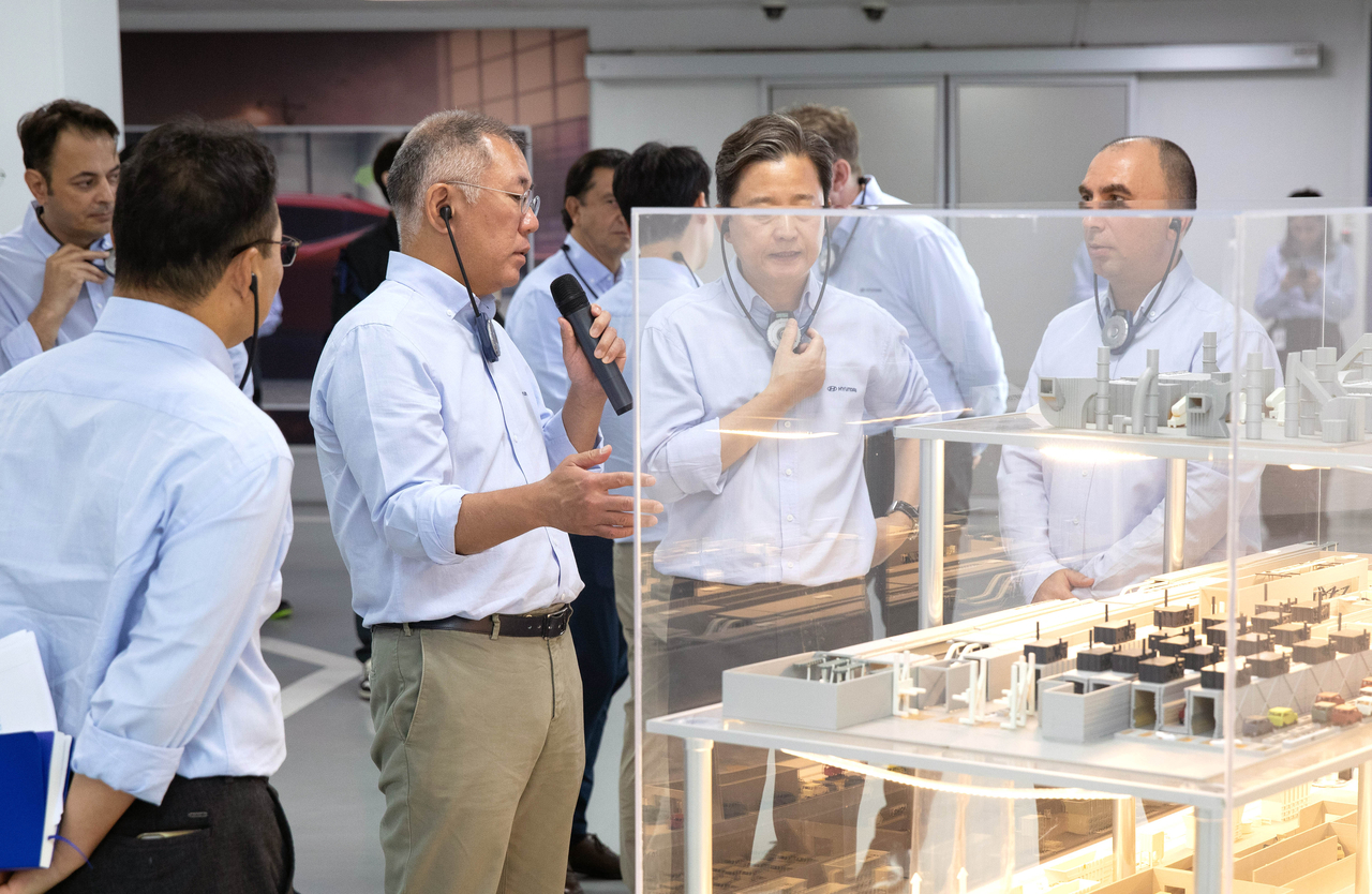 Hyundai Motor Group Chairman Euisun Chung discusses paint quality with employees at the company's Turkey factory, standing before a model of the paint shop. [Hyundai Motor Group]