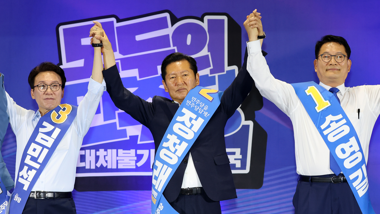 Democratic Party of Korea leadership candidates Rep. Kim Min-seok (from left), Rep. Jung Chung-rae and Rep. Song Young-gil raise their clasped hands at a joint campaign speech event for the party's leadership elections at the Ulsan Exhibition and Convention Center on Sunday. (Yonhap)