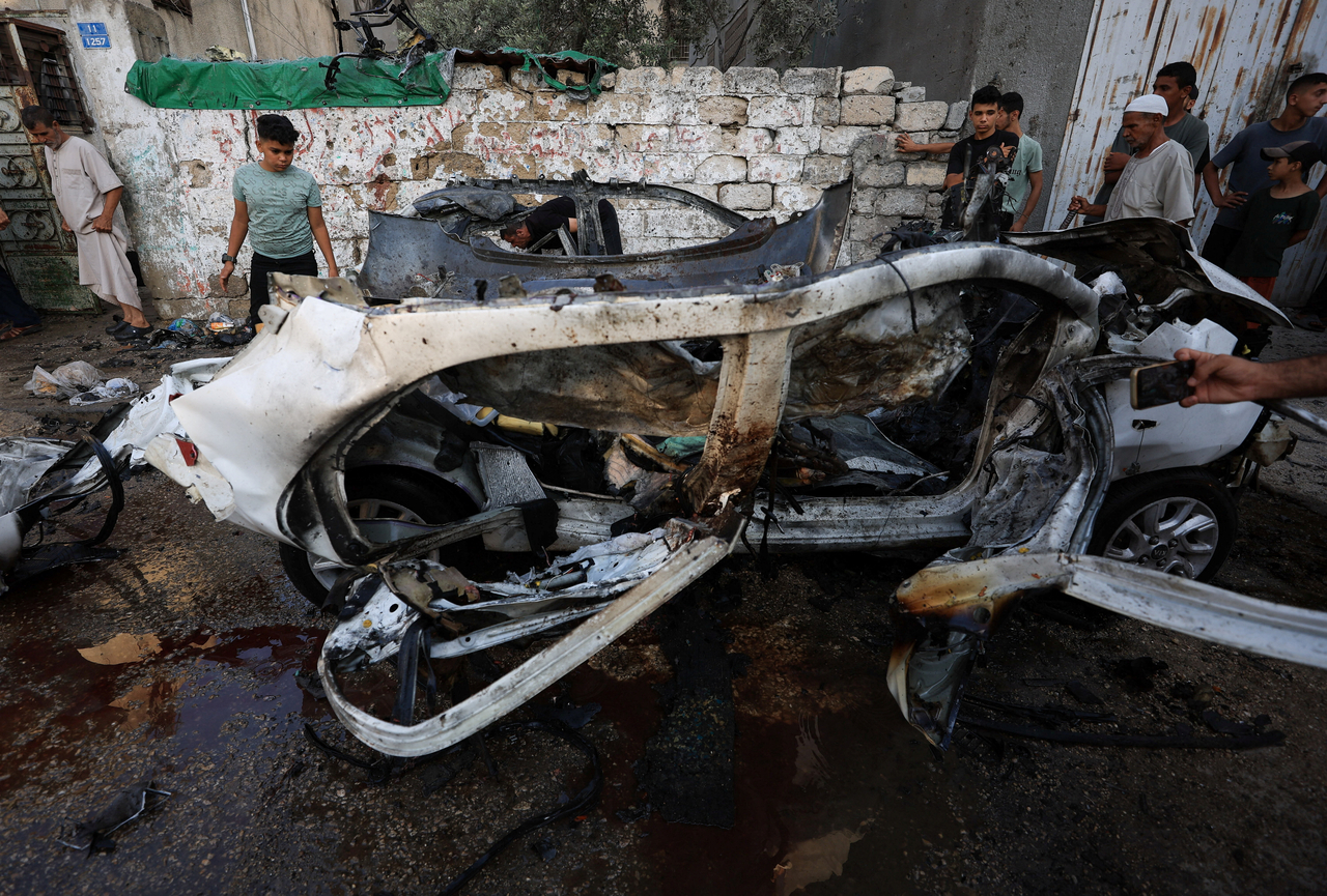 Palestinians inspect the site of an Israeli strike on a vehicle in Gaza City, Sunday. (Reuters-Yonhap)