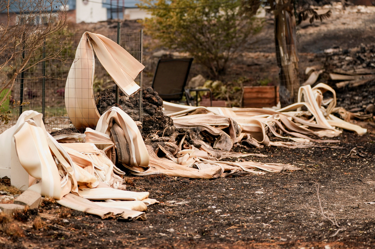 Melted siding lies outside a property damaged by a wildfire, in Spokane, Washington, Sunday. (Reuters-Yonhap)