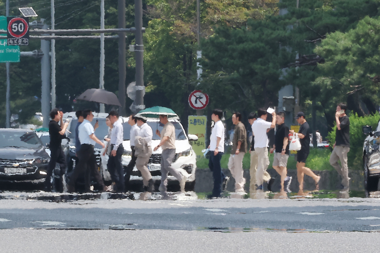 People walk along Yeouidaero in Yeongdeungpo-gu, Seoul, on Monday, amid an ongoing heat wave. (Yonhap)