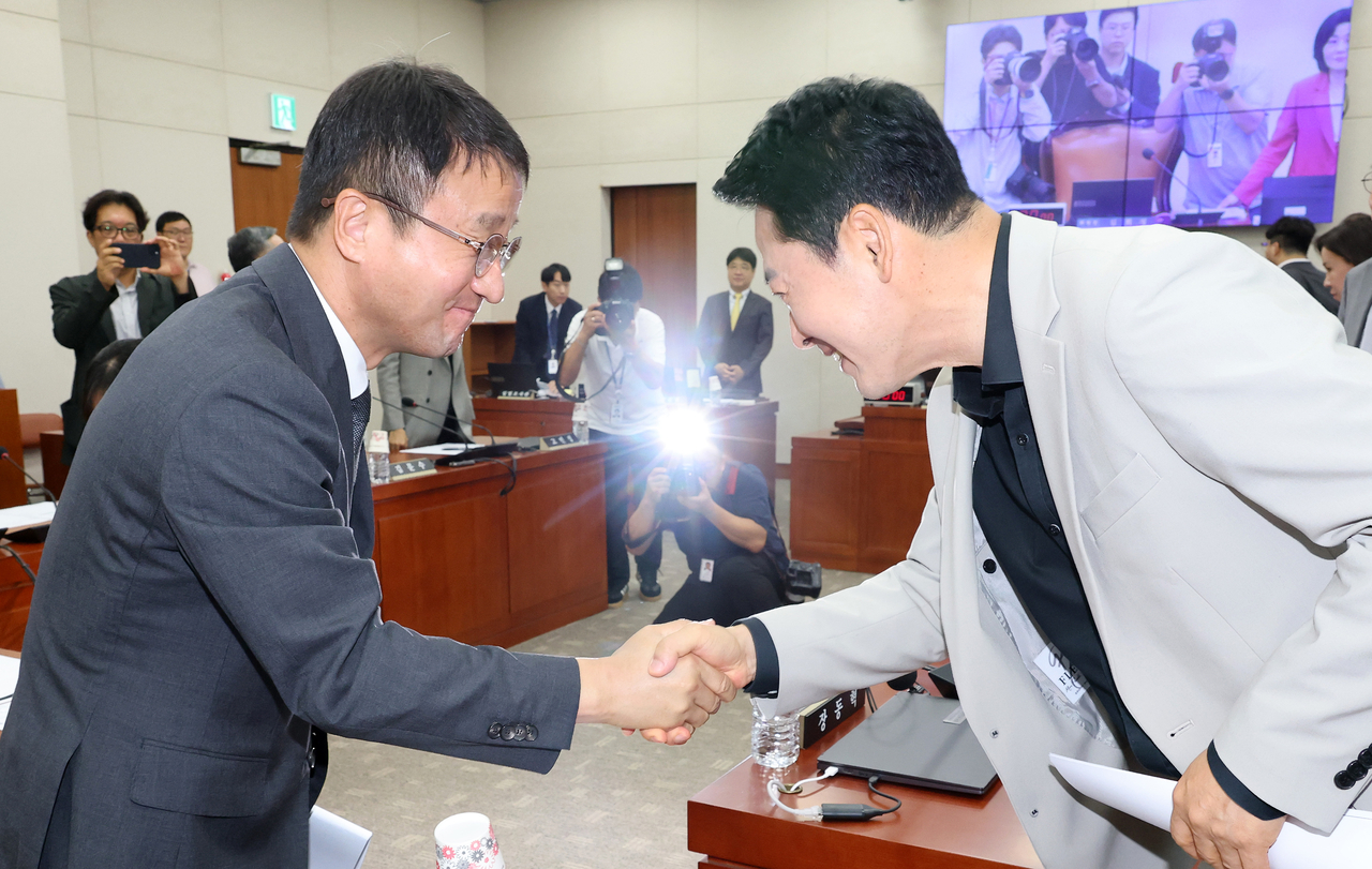 Han Byung-do (left), acting leader and floor leader of the Democratic Party of Korea, shakes hands with People Power Party leader Jang Dong-hyeok at a full session of the National Assembly's Education Committee on Tuesday. [Yonhap]