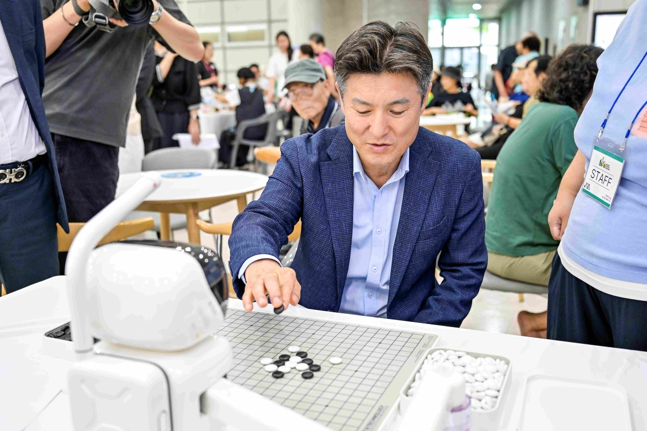 Dobong-gu District Mayor Kim Dong-wook plays a game of omok against an AI robot at the Fourth Industrial Revolution experience booth set up at the exhibition venue.