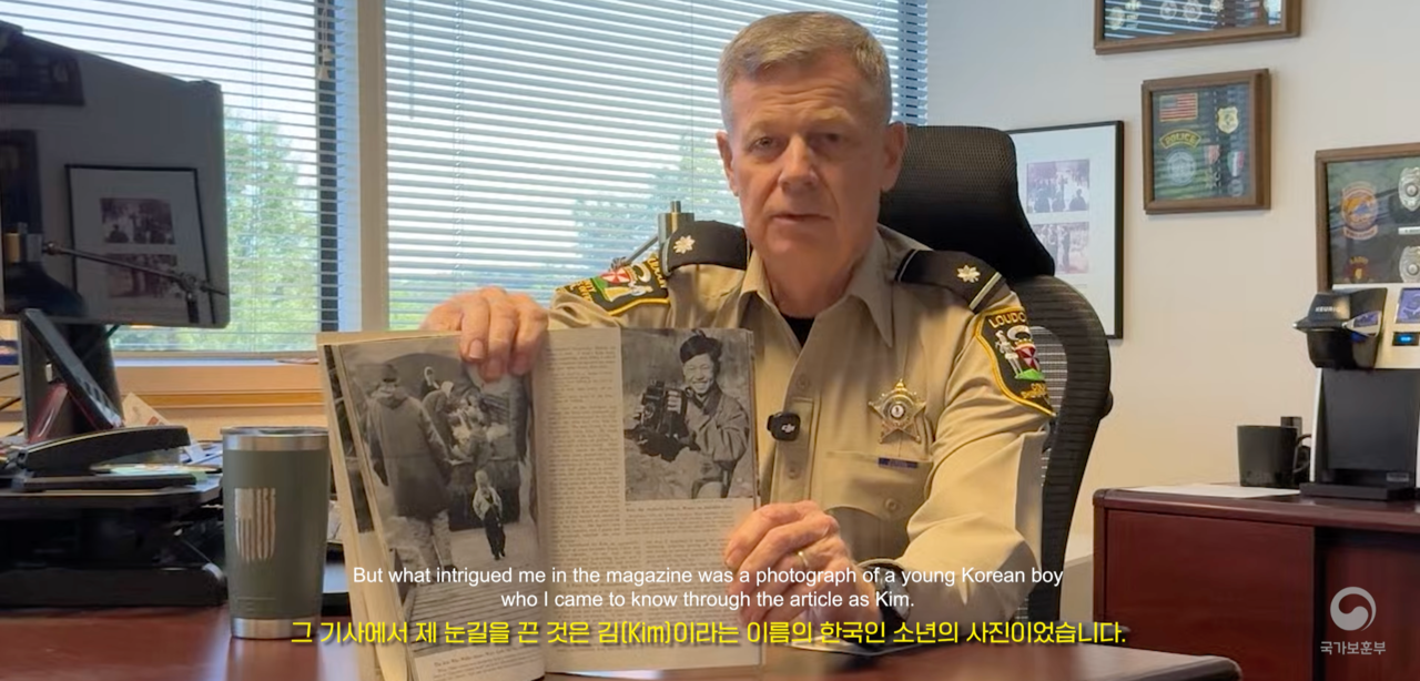 In a video released July 27 by the Ministry of Patriots and Veterans Affairs, Bob Mosier points to a photograph of a Korean boy identified only as Kim in a 1953 National Geographic feature co-authored by his late father, Robert H. Mosier. (Ministry of Patriots and Veterans Affairs)