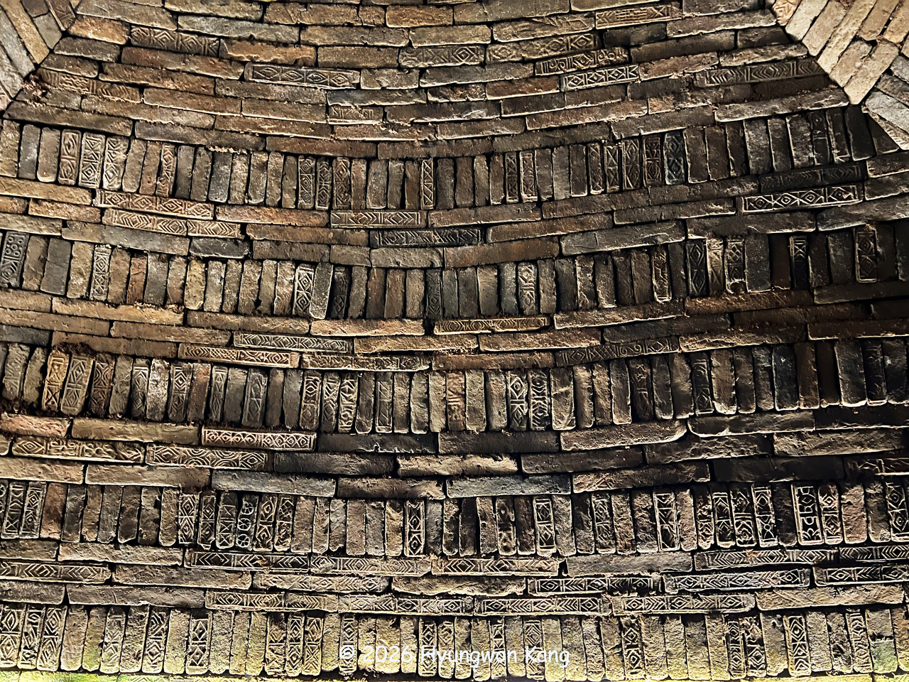 The interior of a reconstructed Rangnang brick-chamber tomb shows walls built in a repeating pattern of three horizontal brick courses and one vertical course, converging into a conical ceiling that supports the massive earthen mound above, at Rangnangguk Museum in Pyongyang. (Hyungwon Kang)