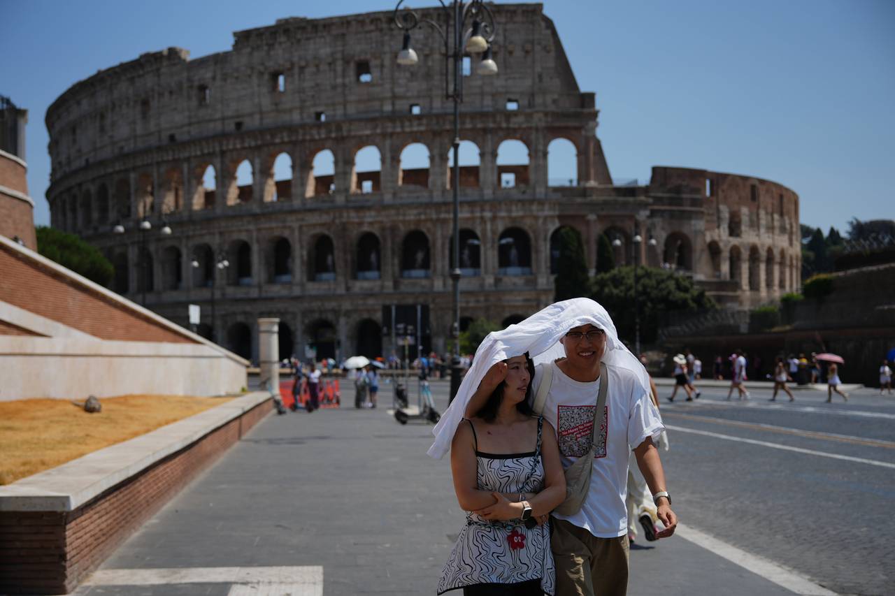 Tourists take shelter as they walk in front of the Rome'a ancient Colosseum, Saturday. (AP-Yonhap)