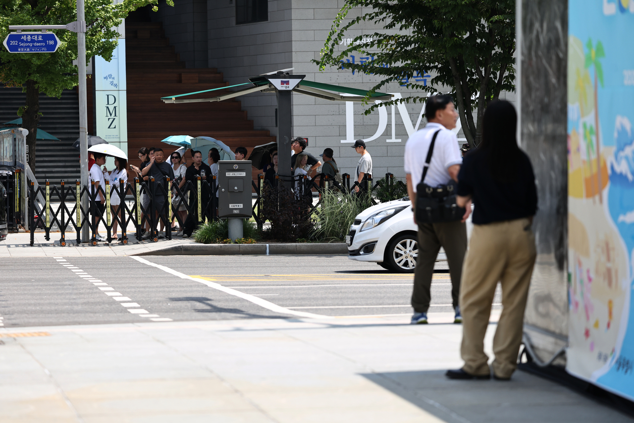 Commuters in Jongno, central Seoul, use parasols and stand in the shade Thursday morning, as the city's temperature was forecast to reach 39 degrees Celsius. (Yonhap)