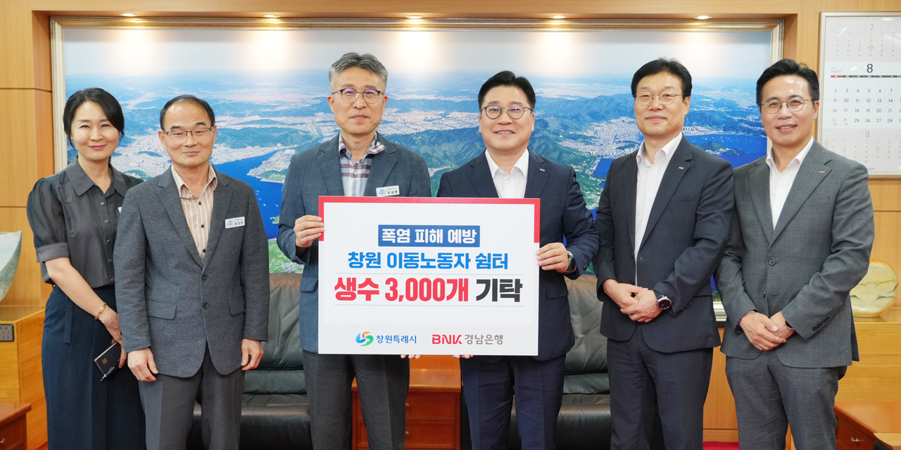 BNK경남은행 허종구(오른쪽 세 번째) 부행장이 창원시 조성환(오른쪽 네 번째) 경제일자리국장에게 이동노동자 지원을 위한 생수 3000개 기탁 증서를 전달하고 관계자들과 기념촬영을 하고 있다. [경남은행 제공]