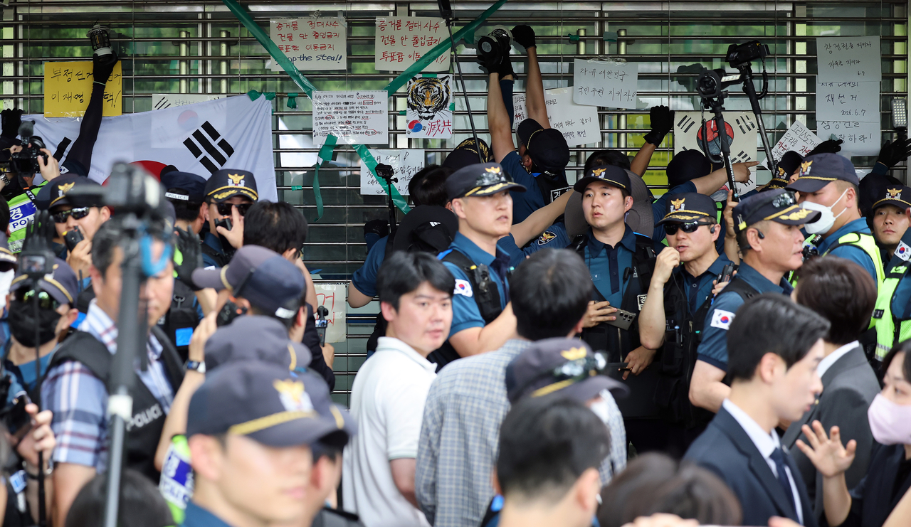 Police mobile unit officers clear objects blocking an entrance and open the doors at the ballot-counting center at Olympic Park's handball arena in Songpa-gu, Seoul, on July 2. [Yonhap]