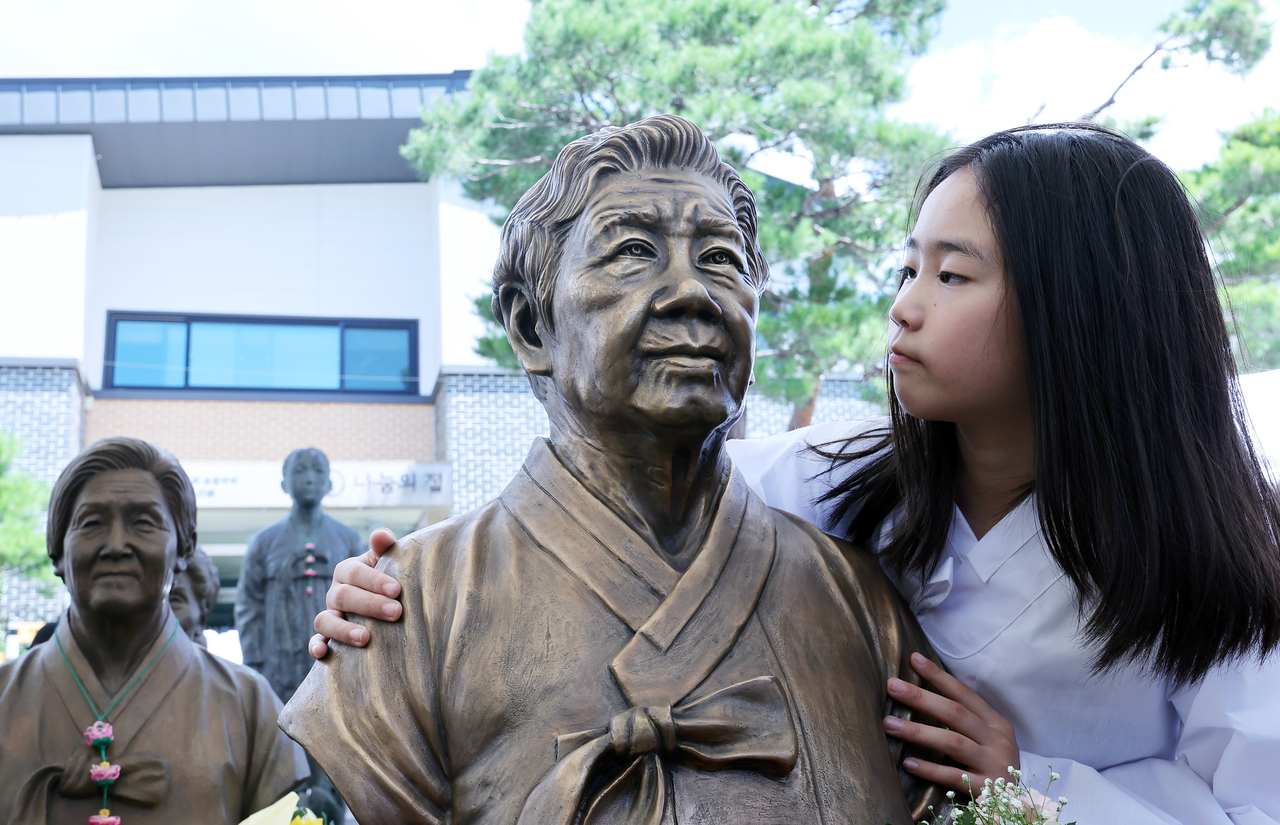 A child looks at a bust of the late Kang Il-chul, a survivor of sexual slavery imposed by the Japanese military during World War II, at a memorial ceremony held Saturday at the House of Sharing in Gwangju, Gyeonggi Province. The event came ahead of Aug. 14, South Korea’s national memorial day honoring the victims. (Yonhap)
