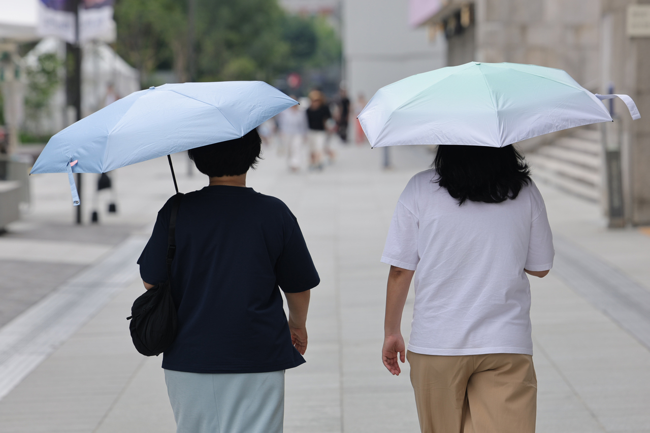 Pedestrians walk under umbrellas at the Gwanghwamun Square in Seoul on July 31. This photo is not related to the story. (Yonhap)