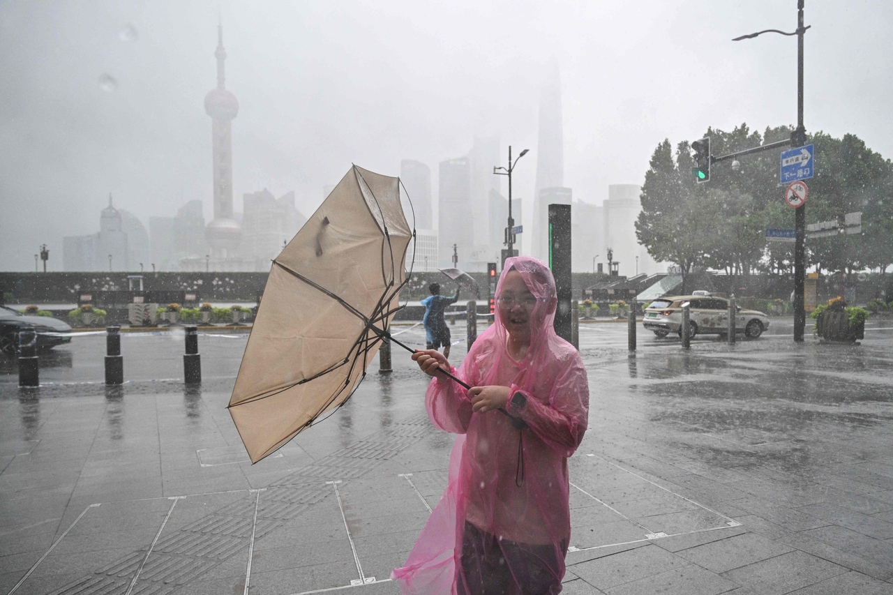 People use umbrellas to shelter from the rain as they walk on the Bund a day after Typhoon Dolphin made landfall in Shanghai on Monday. (AFP-Yonhap)