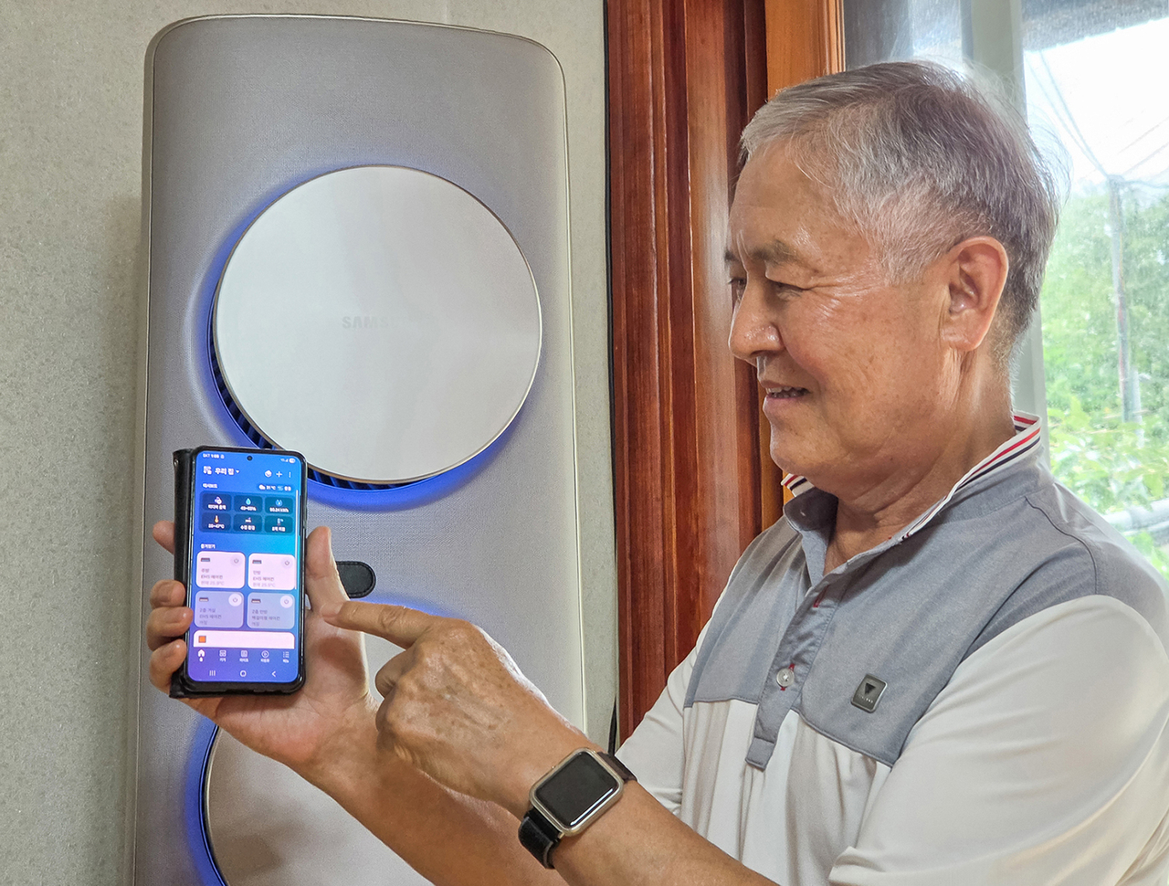 Yang Chang-hui, 74, operates the EHS all-in-one heat pump via SmartThings at the field test lab home. [Samsung Electronics]