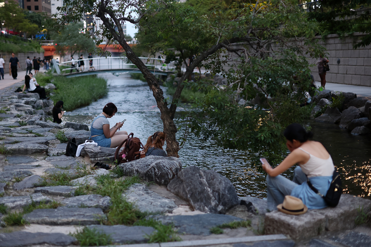People enjoy their time along Cheonggyecheon, Seoul on July 27. (Yonhap)
