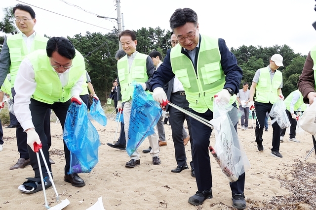 Minister of Interior and Safety Yun Ho-jung (right) collects trash along the coast at the Daehangmin Saedanjang event held near Gungpyeong Port in Hwaseong, Gyeonggi Province, in September last year. [Ministry of Interior and Safety]