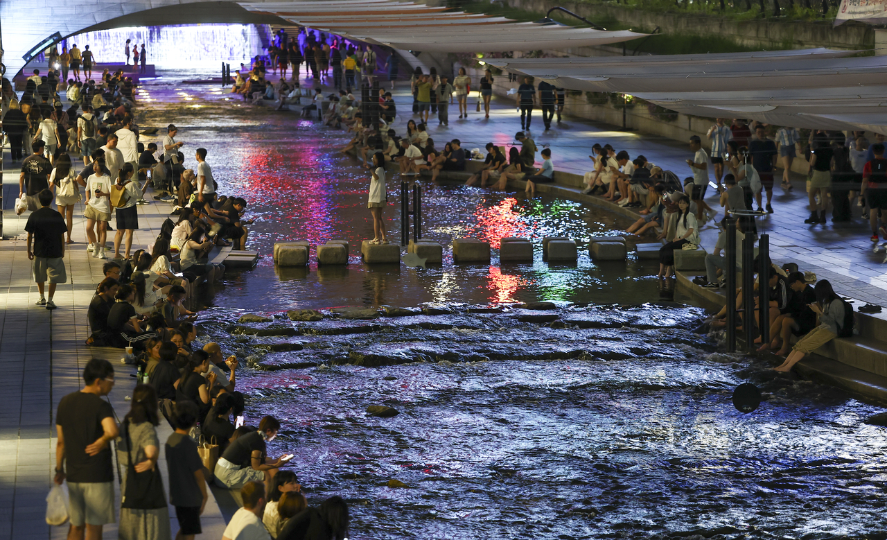 People dip their feet in the water to cope with the heat along Cheonggyecheon, Seoul, July 12. (Yonhap)