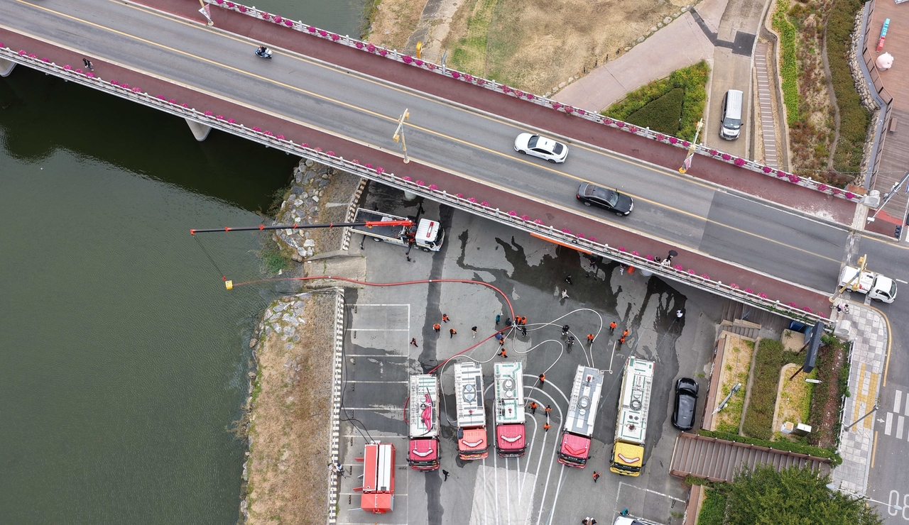 Fire trucks collect water from the Miryang River in Miryang, South Gyeongsang Province, on Wednesday, as firefighting resources from across the country are deployed to help supply agricultural and household water to drought-stricken areas in the province. (Yonhap)