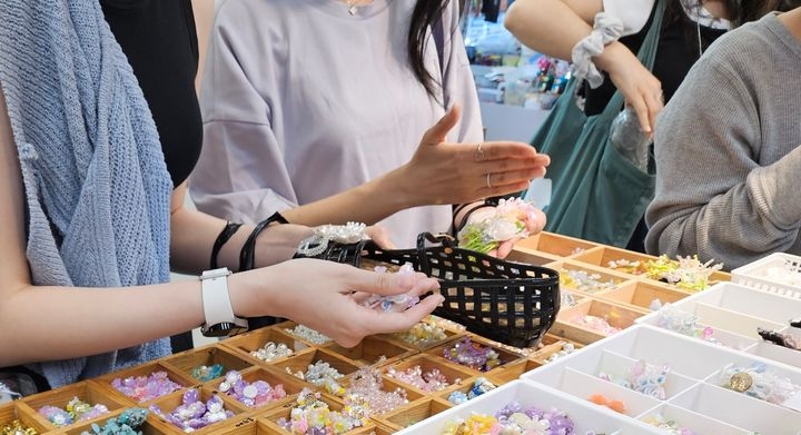 Visitors decorate jelly shoes with charms at Dongdaemun Market in Seoul on May 27. (Newsis)