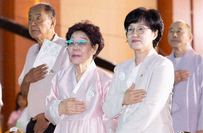 Lee Yong-soo (center), survivor of Japan's wartime sexual slavery, salutes to the national flag, alongside the Minister of Gender Equality and Family Won Min-kyong (right) at a memorial ceremony at the Kim Koo Museum & Library in Seoul on Friday. (Yoon Chang-bin/The Korea Herald)