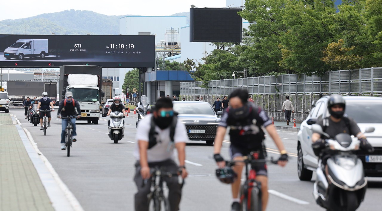 Workers on the morning shift leave early from the Myeongchon gate of Hyundai Motor's Ulsan factory in Buk-gu, Ulsan, on Wednesday, as a four-hour partial strike cuts short their workday. [Yonhap]