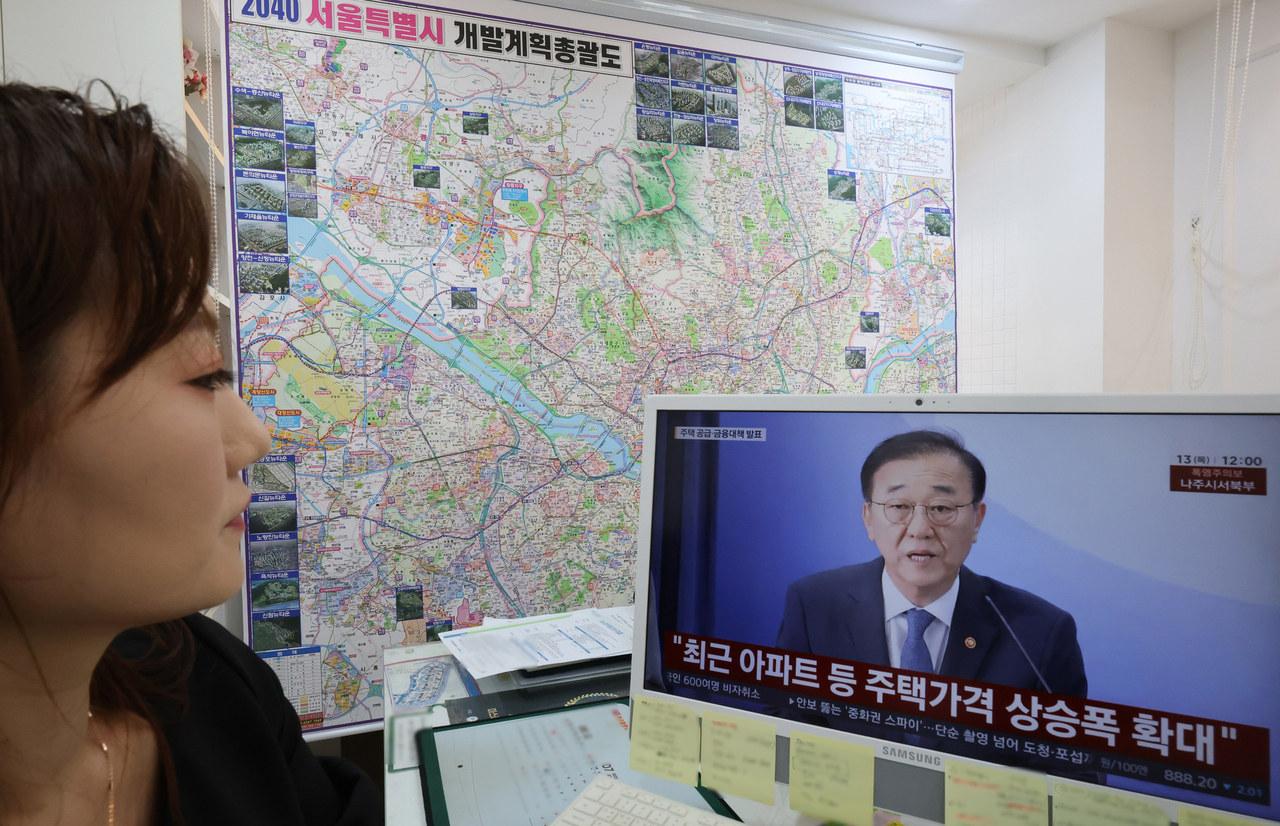 13일 서울 한 부동산 중개업소에서 관계자가 정부의 ‘전월세 및 매매시장 안정을 위한 주택 신속공급 방안’과 ‘부동산 시장 안정을 위한 금융 종합대책’을 TV로 보고 있다. [연합]