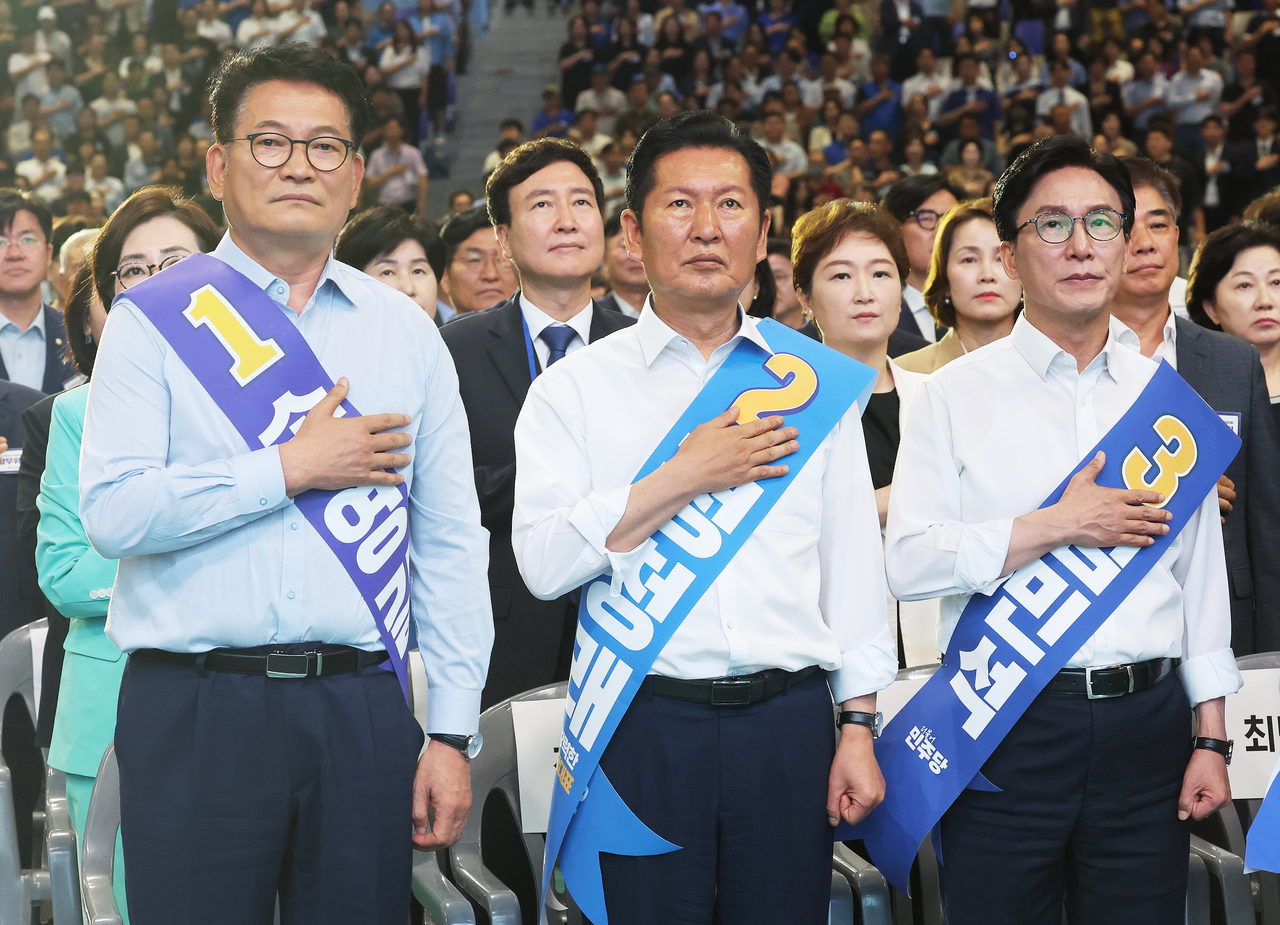 Democratic Party of Korea leadership candidates Song Yeong-gil, Jung Chung-rae and Kim Min-seok salute the national flag at a joint campaign speech event for party leader and supreme council member candidates at Suwon General Stadium indoor gymnasium in Suwon, Gyeonggi Province, on Sunday. [Yonhap]