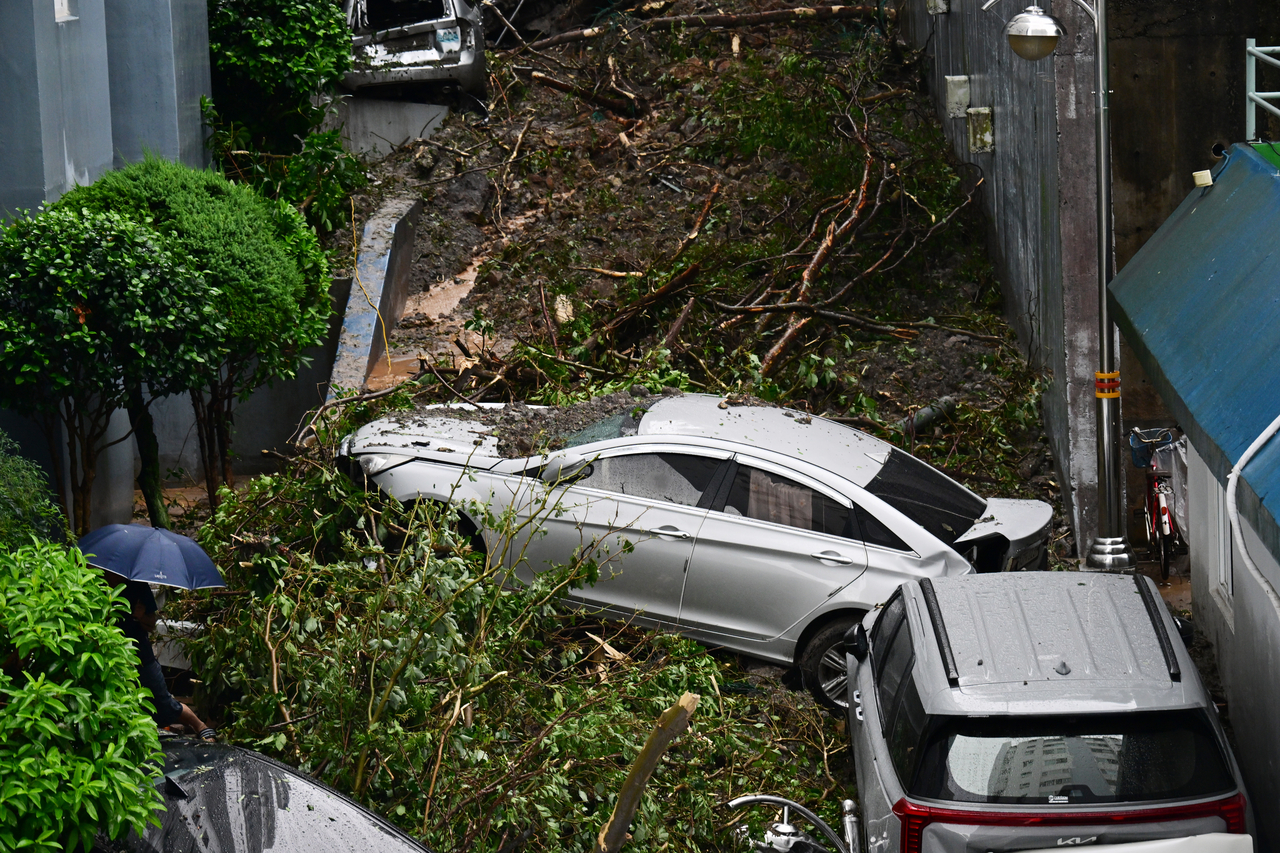Vehicles are tangled together after a landslide sent mud, trees and other debris down near a residential area in Okpo-dong, Geoje, South Gyeongsang Province, Monday. (Yonhap)