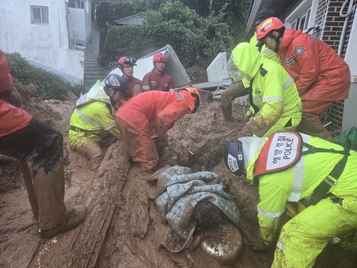 Rescue officers rescue a 64-year-old woman who was trapped in her home by a landslide in Tongyeong, South Gyeongsang Province, Monday. (Tongyeong Coast Guard via Newsis)