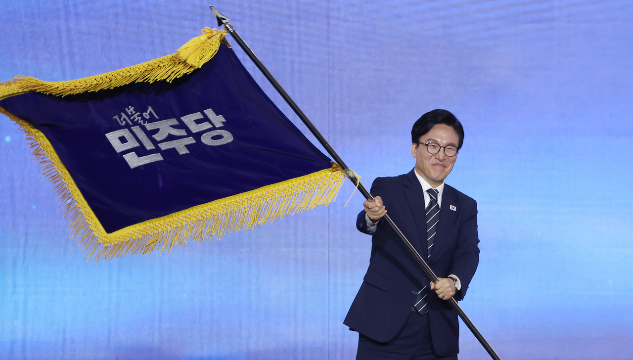 Rep. Kim Min-seok waves the Democratic Party's flag after the party announced his victory in Daejeon on Monday. (Yonhap)