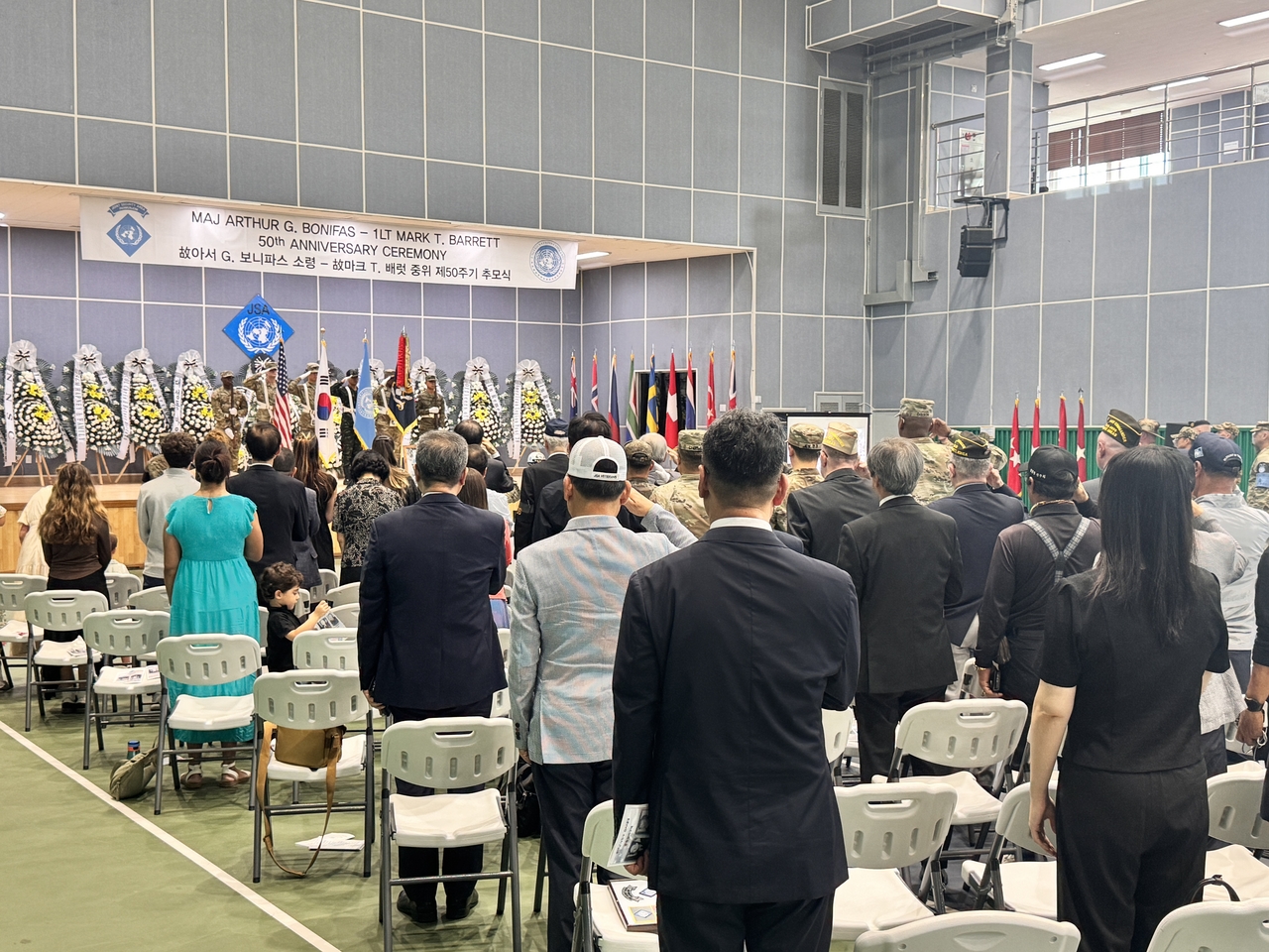 Attendees stand to pay tribute during a memorial ceremony at Park Gym in the Joint Security Area in Gyeonggi Province on Tuesday. (Joint Press Corps)