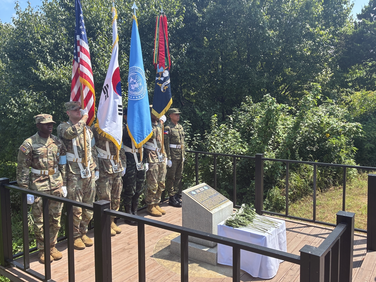 Joint Security Area and United Nations Command personnel hold the flags of South Korea, the United States, the UNC and the JSA Security Battalion at a memorial site inside the JSA in Gyeonggi Province on Tuesday. (Joint Press Corps)