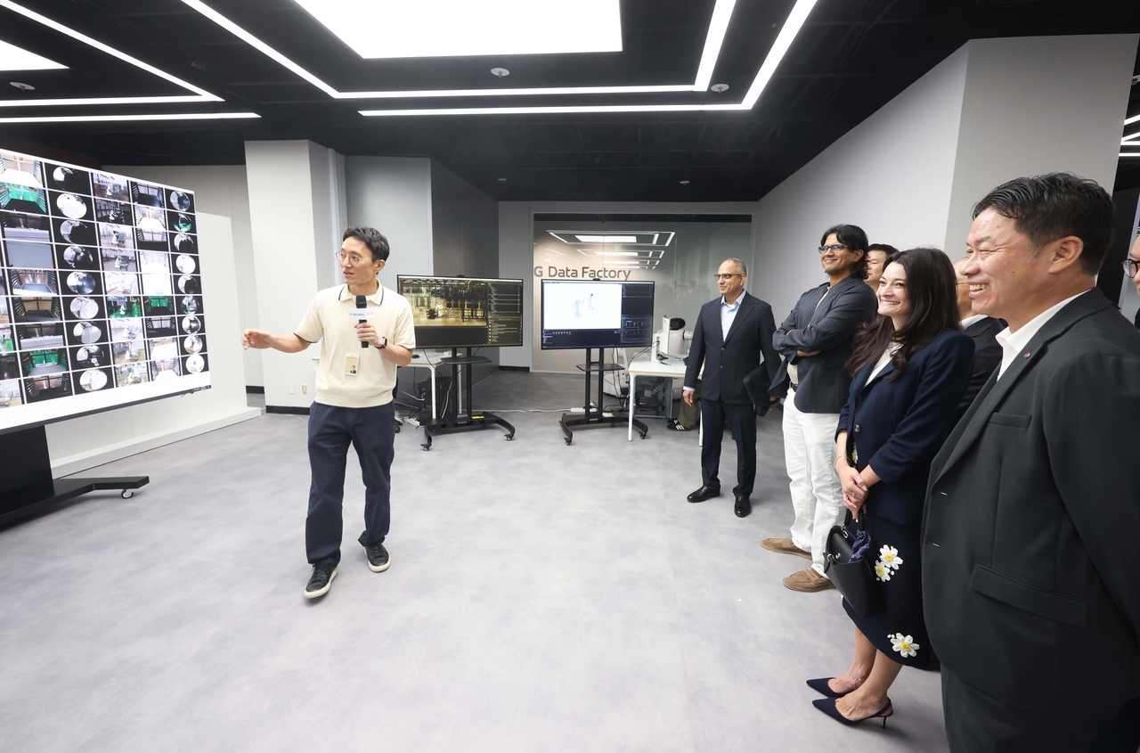 LG Electronics CEO Lyu Jae-cheol (first from right) and Madison Huang, senior director of product marketing for Nvidia's omniverse and robotics, examine a data augmentation and synthesis solution at LG’s data factory under construction in Seocho-gu, Seoul, Tuesday. (LG Electronics)