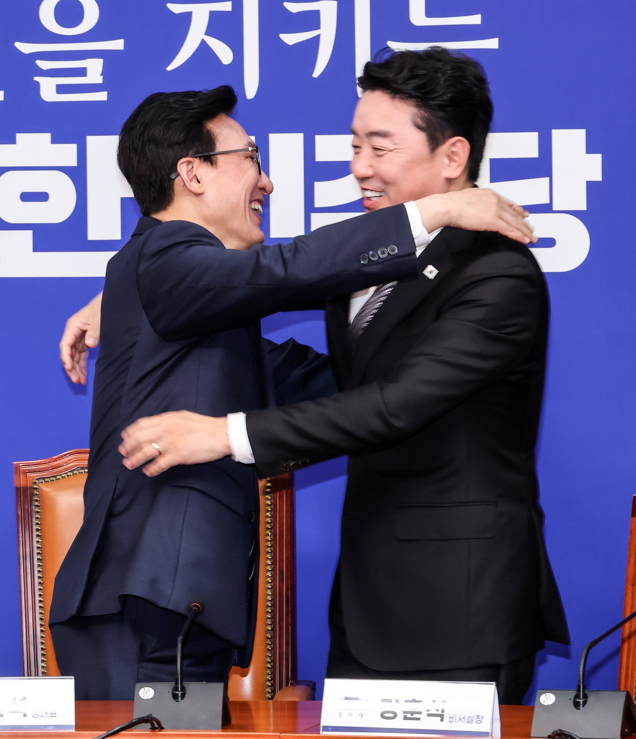 더불어민주당 김민석(왼쪽) 대표가 18일 국회에서 취임 축하 인사차 방문한 강훈식 대통령비서실 비서실장을 만나 반갑게 포옹하고 있다.  [연합]