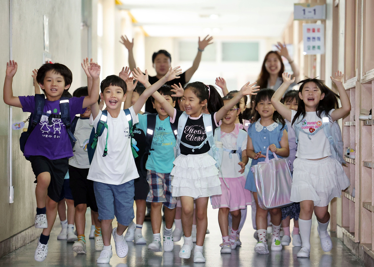 First-graders at an elementary school in Suwon, Gyeonggi Province, rush out of their classrooms as their summer vacation begins on July 27. (Yonhap)