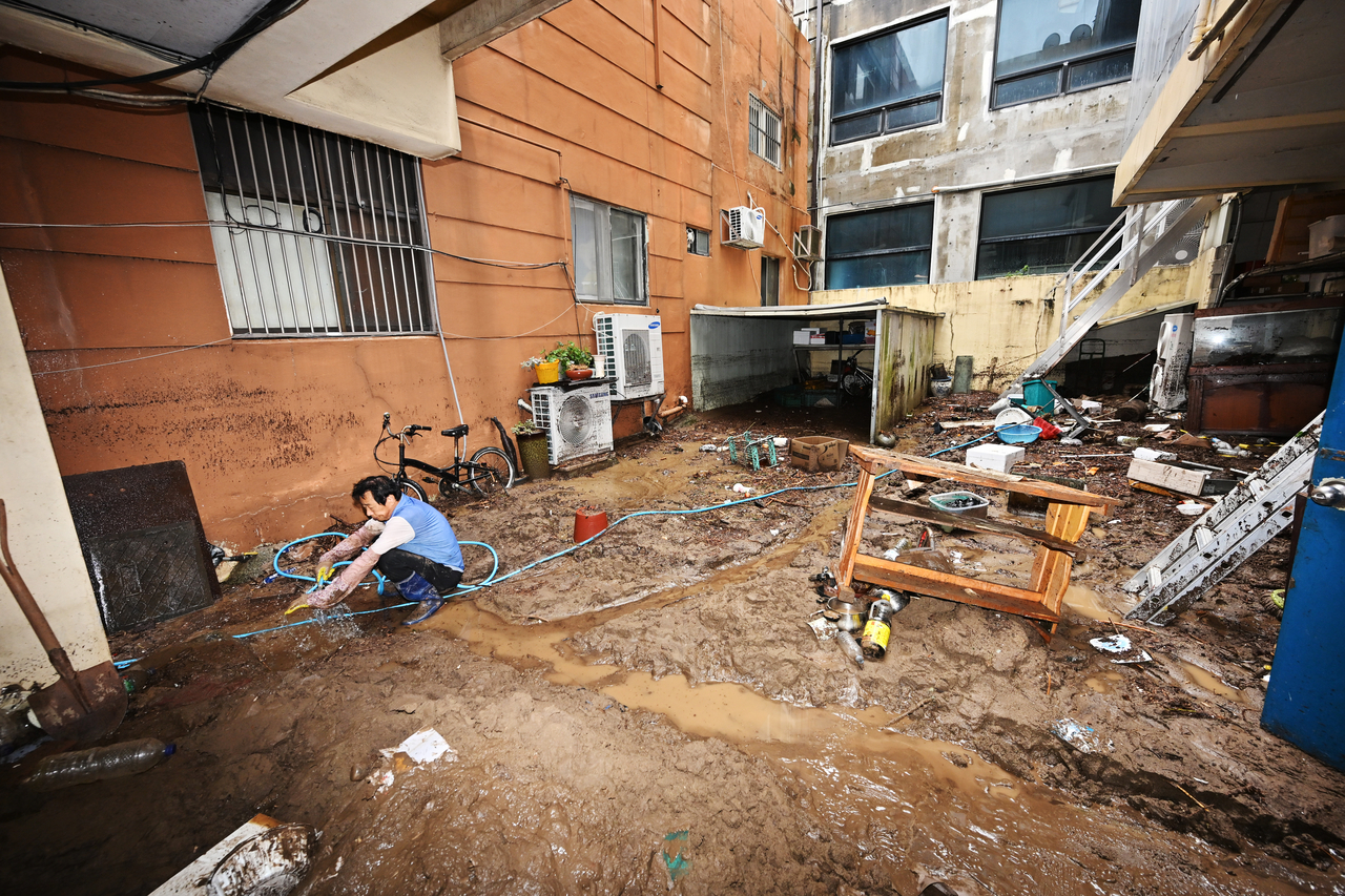 Residents clear mud and waterlogged belongings from flooded shops and homes in Okpo-dong, Geoje, South Gyeongsang Province, on Tuesday, after record-breaking heavy rain caused widespread damage in the area. [Newsis]