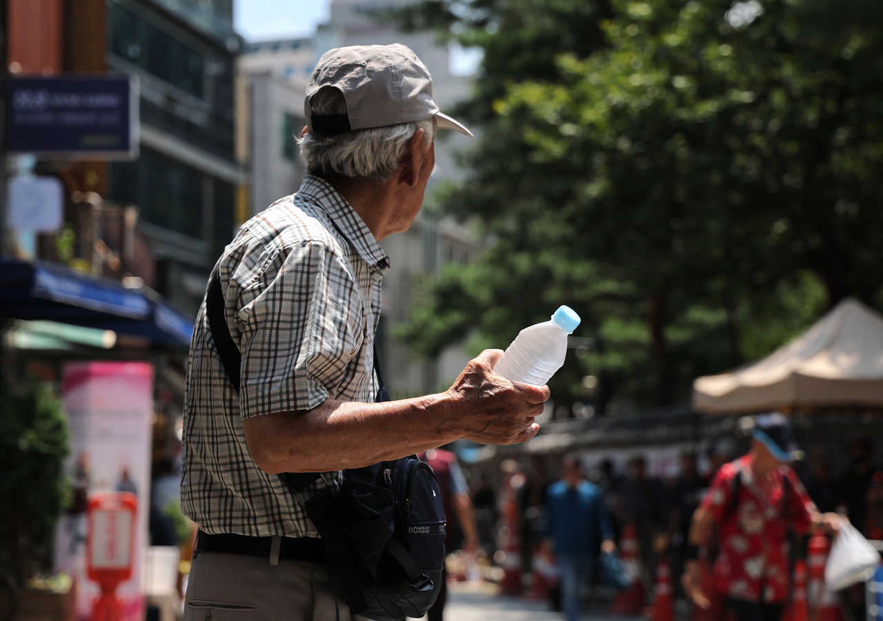 A senior citizen walks with a water bottle in his hands in Jongno-gu, central Seoul, on Aug. 3. (Yonhap)
