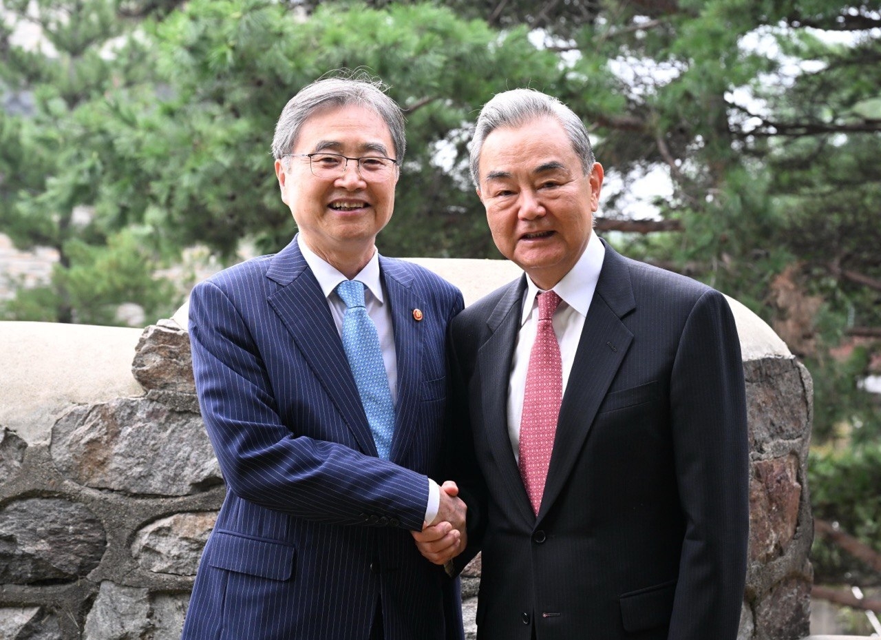 President Lee Jae Myung (right) shakes hands with Chinese Foreign Minister Wang Yi during a walk along the Dasan Seonggwak-gil trail on Namsan in Seoul on Thursday. The two took a morning walk after breakfast, following their meeting and dinner the previous day. (Repblic of Korea Ministry of Foreign Affairs)