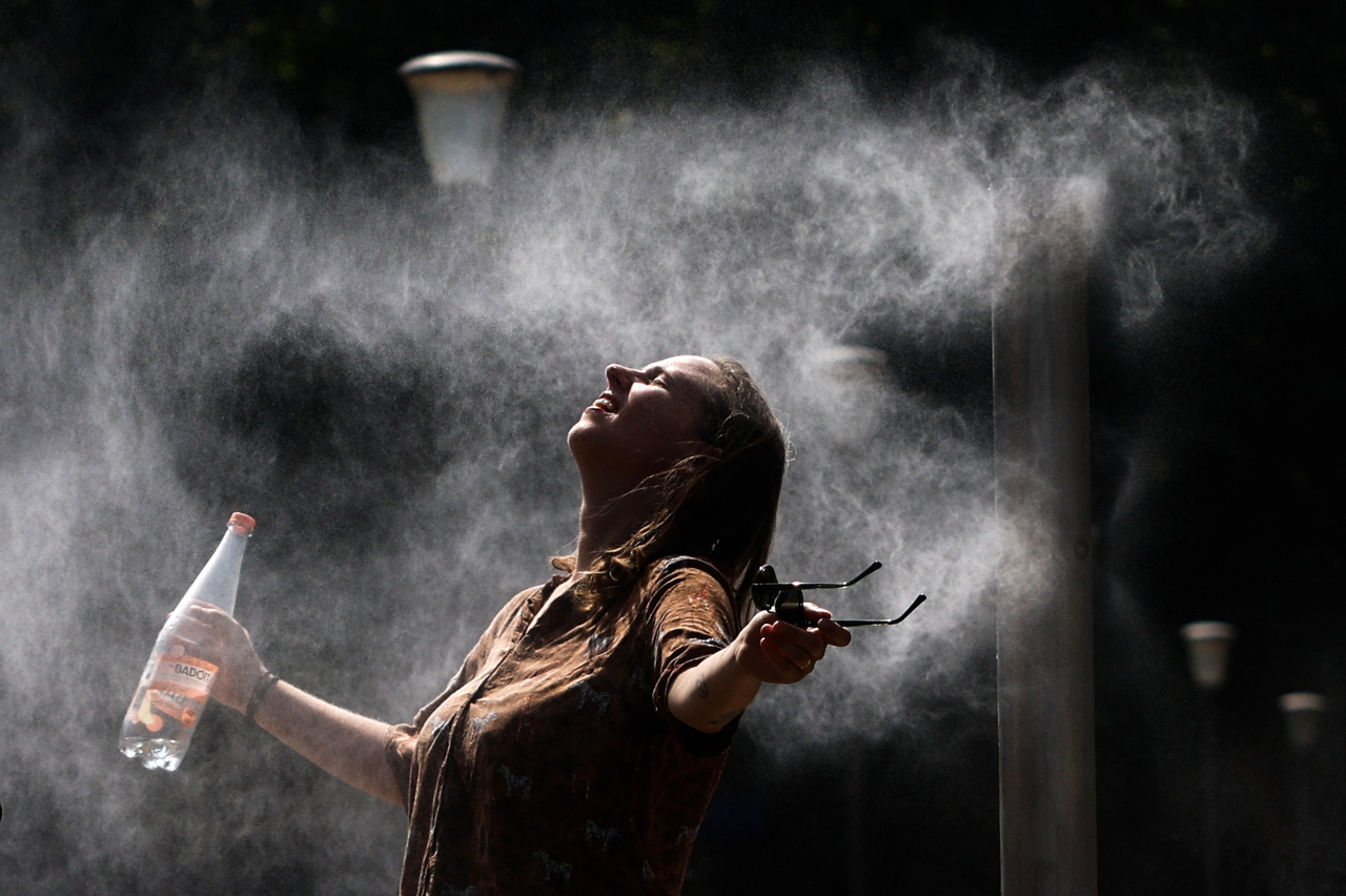 A person reacts as she cools off under a misting system at Parc de Bercy during the heat wave, in Paris, France, Aug. 14. (EPA-Yonhap)