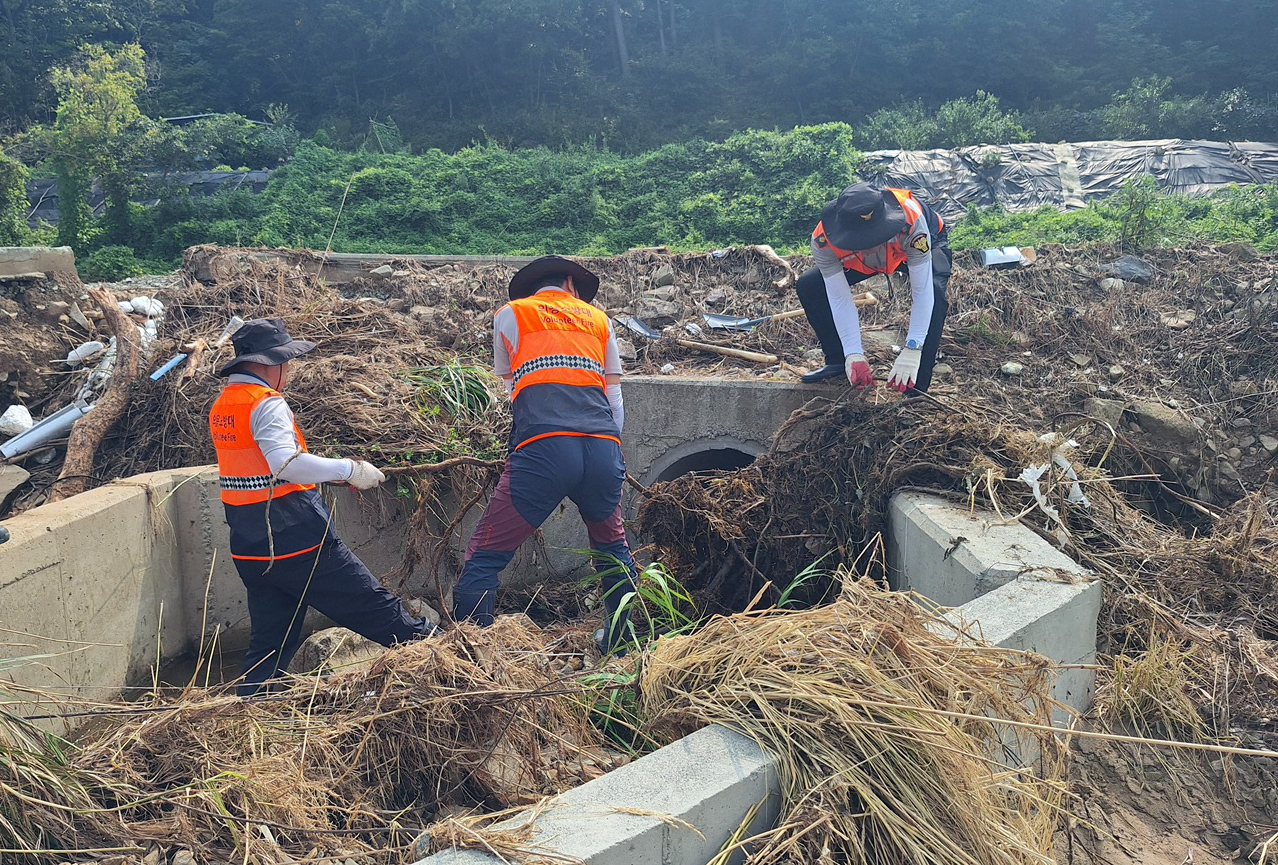 Volunteer firefighters from Daejeon clear debris swept in by heavy rain at a flood-hit site in Geoje, South Gyeongsang Province, Saturday. (Yonhap)