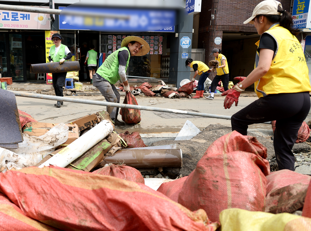 Volunteers clear water-damaged goods and debris from flooded shops in Okpo-dong, Geoje, South Gyeongsang Province, Friday. (Yonhap)