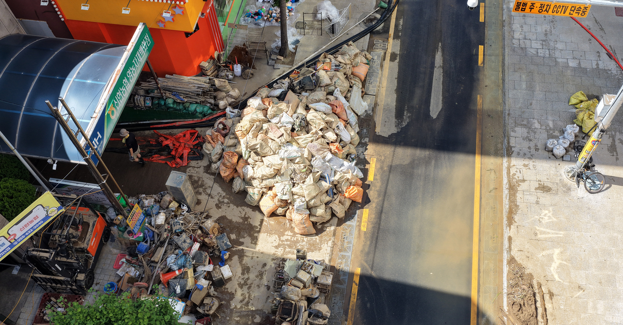 Debris and damaged belongings left by the floodwaters line a street in Gohyeon-dong, Geoje, South Gyeongsang Province, on Wednesday. [Yonhap]