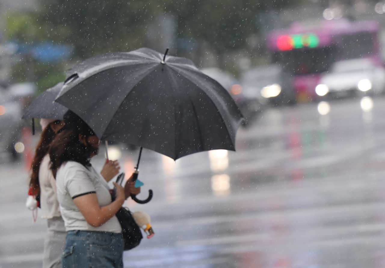 Tourists cross a road under umbrellas in central Seoul on Saturday. (Yonhap)