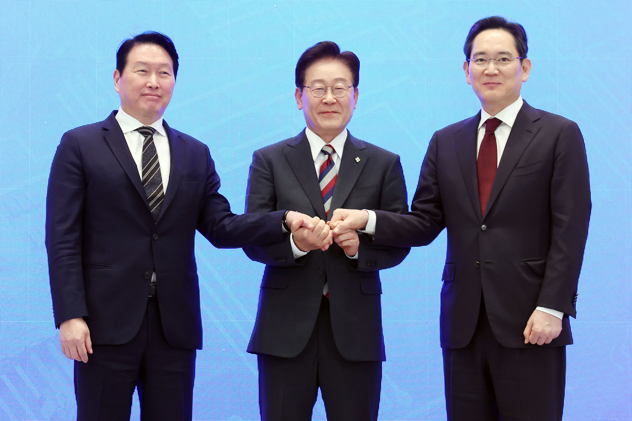 이재명 대통령과 이재용 삼성전자 회장, 최태원 SK그룹 회장이 지난 6월 29일 청와대에서 열린 3대 메가프로젝트 국민보고회에서 기업 투자계획 발표 후 손을 잡고 있다. [연합]