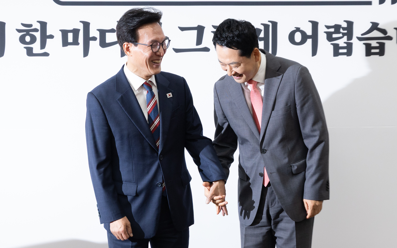 Democratic Party of Korea chair Rep. Kim Min-seok (left) holds hands with People Power Party chair Rep. Jang Dong-hyeok in the National Assembly on Monday. (Yoon Chang-bin/The Korea Herald)