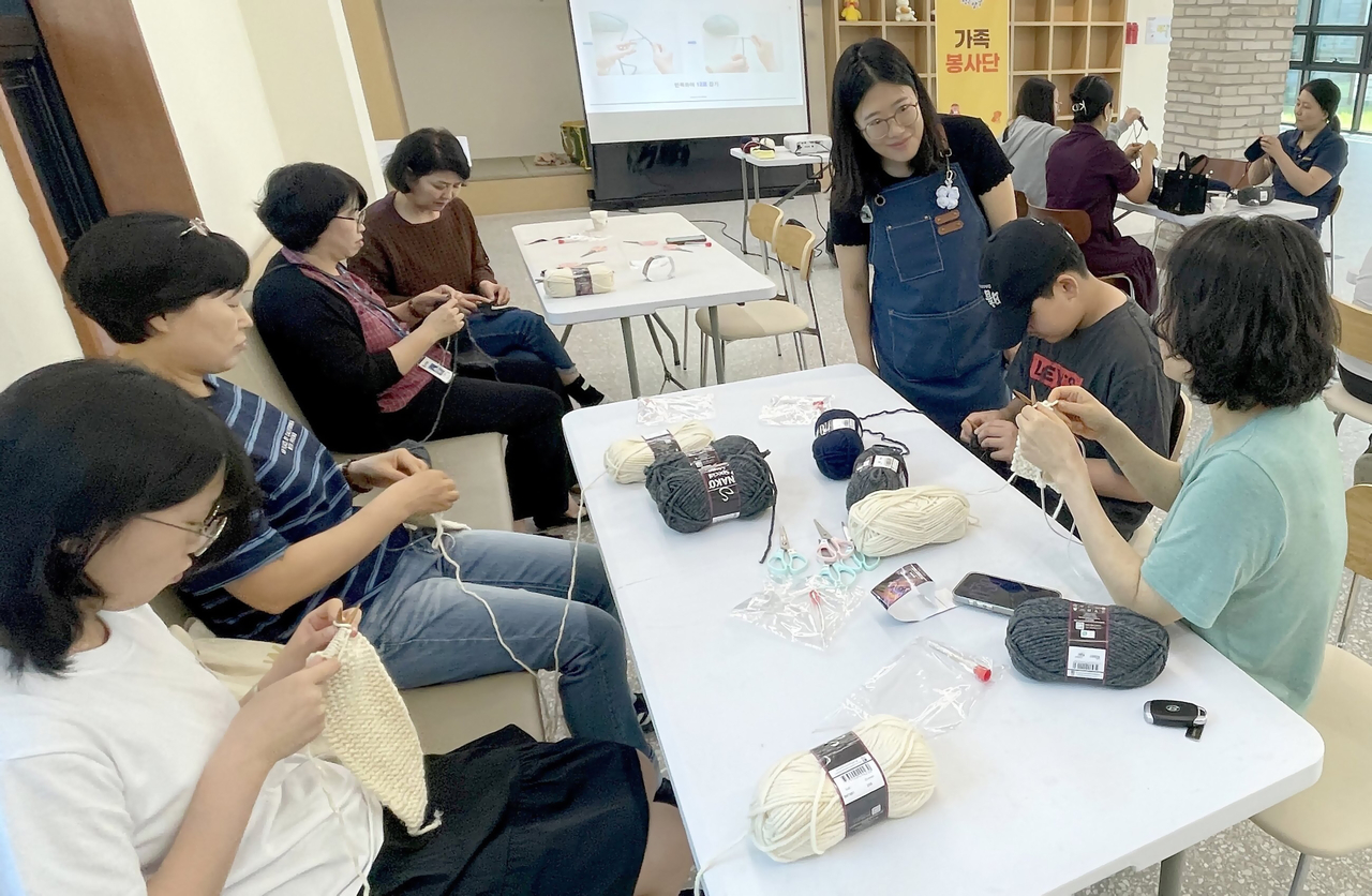 Family volunteers in Yanggu-gun knit scarves for neighbors in need.